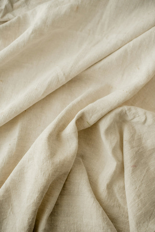 Close view of undyed washed flax linen, showing the open weave and soft folds.